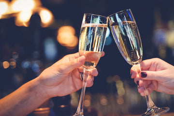 Two glasses of champagne being clinked together with a blurred background