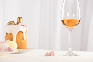 Glass of sweet wine next to a small cake on a white background