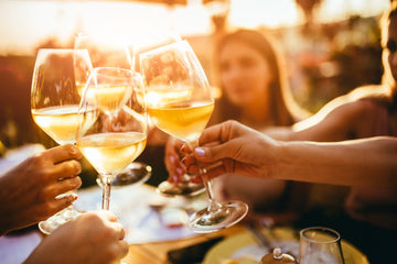 People toasting with white wine glasses at a social gathering