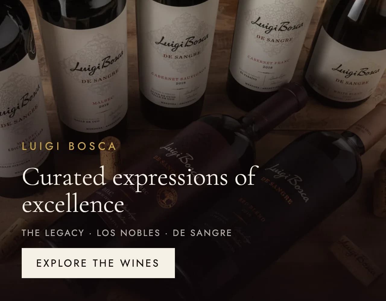 어두운 테이블 위의 Luigi Bosca 와인병. 탁월함을 담아 엄선한 The Legacy, Los Nobles, De Sangre.