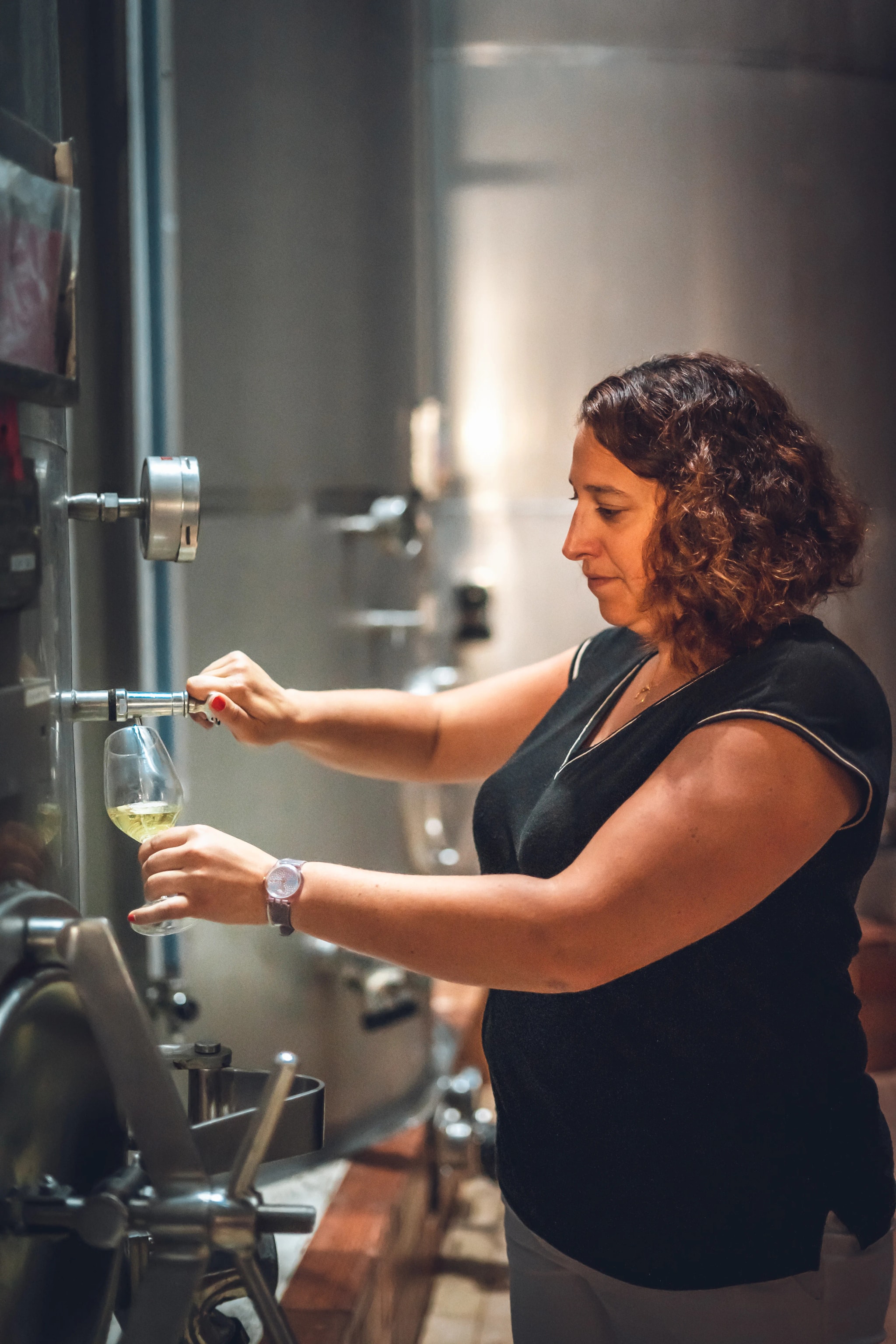 A Wolfberger winemaker drawing a sample from a stainless steel vat