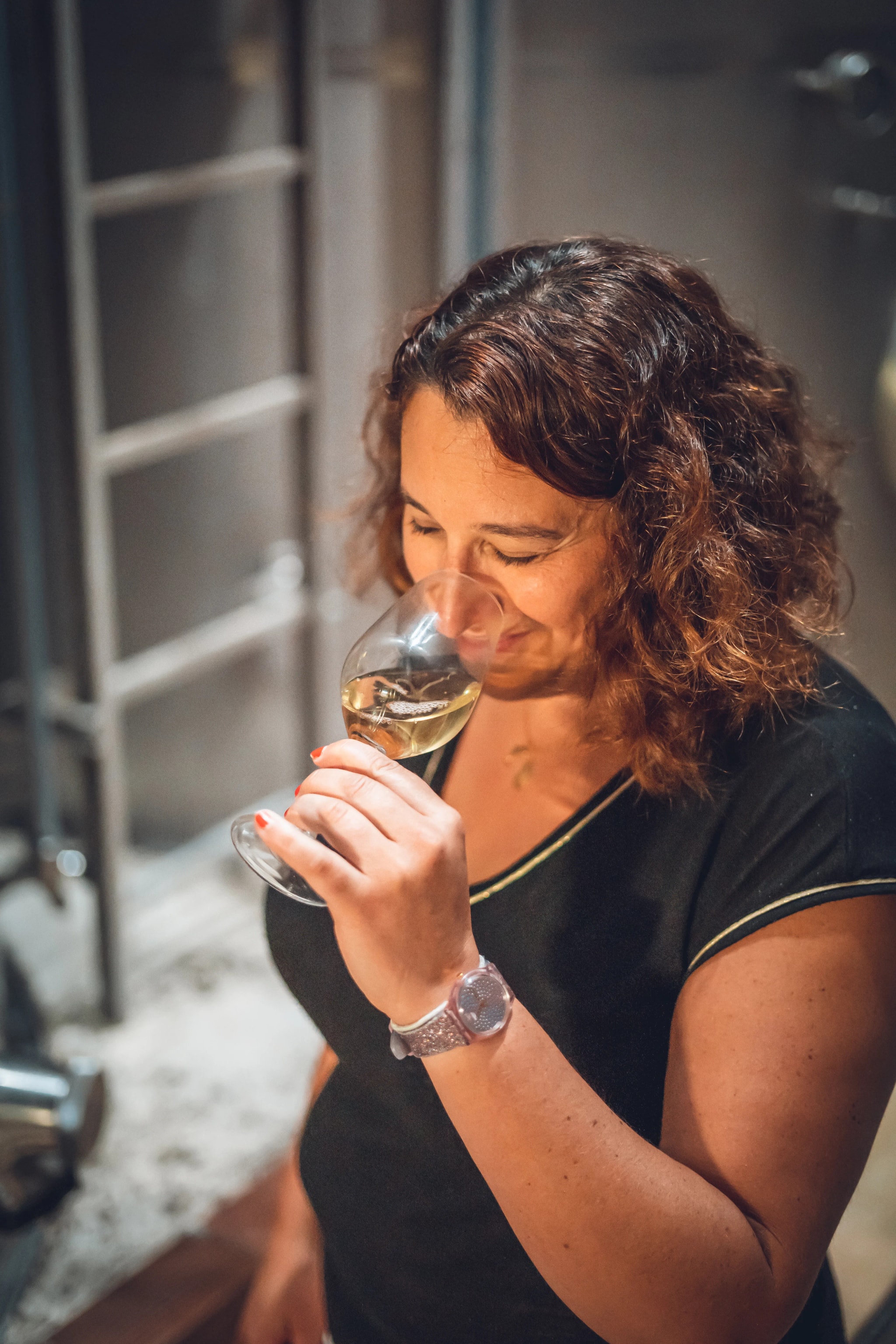 A Wolfberger winemaker nosing a glass of white wine in the cellar