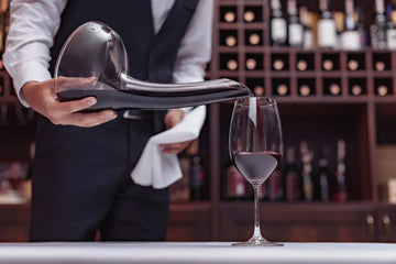 A sommelier decants and pours red wine gently to enhance aeration, soften tannins, and reveal deeper aromas.