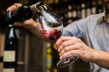 Close up of a man pouring red wine into a wine glass