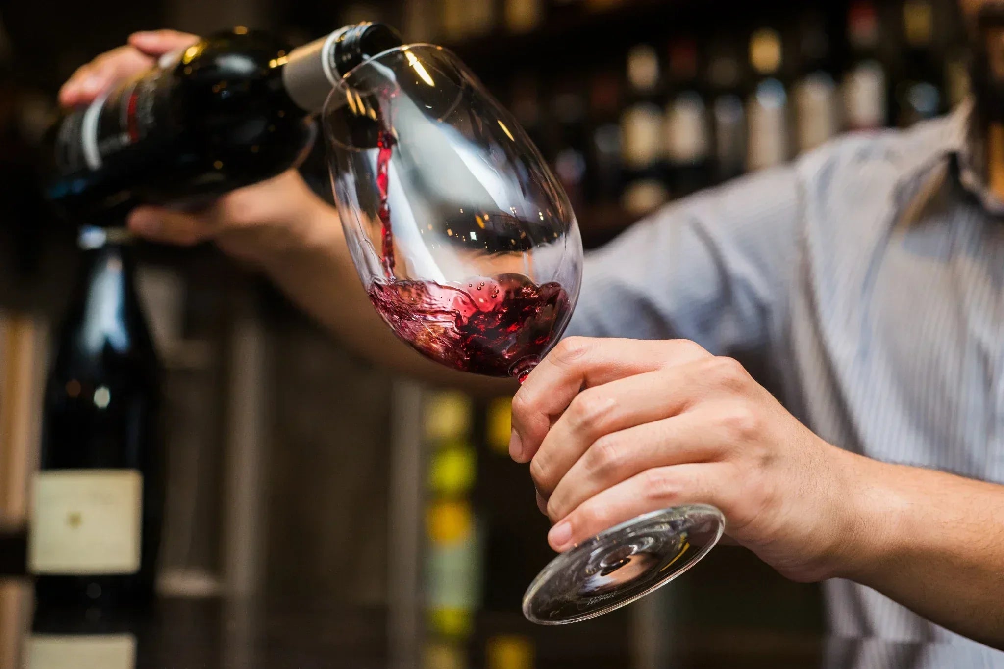 Close up of a man pouring red wine into a wine glass