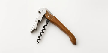 Use the double-hinged corkscrew to remove the cork smoothly in two controlled steps, ensuring a clean and professional extraction.